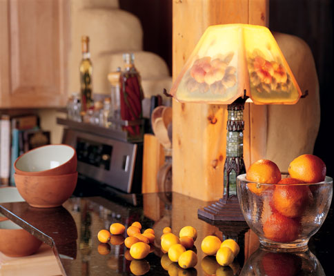 
The floral-shade lamp was a real find at a local consignment shop. The kitchen is separated from the entry way by a stair-stepped cob wall.
